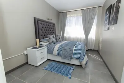 a bedroom with a bed and a window and a rug at AfricaLove on Tiger in Pretoria