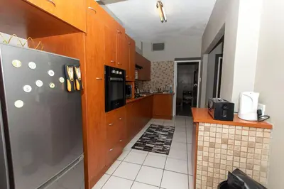 a kitchen with wooden cabinets and a black refrigerator at AfricaLove on Tiger in Pretoria