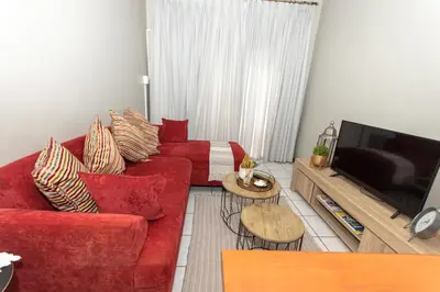 a living room with a red couch and a television at AfricaLove on Tiger in Pretoria