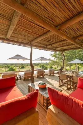 an outdoor patio with red pillows and tables and umbrellas at Baobab Ridge in Klaserie Private Nature Reserve