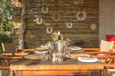 a wooden table with a bottle of wine and glasses at Baobab Ridge in Klaserie Private Nature Reserve