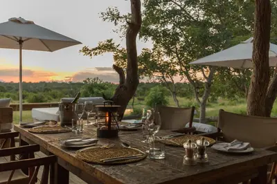 a wooden table with plates and glasses and an umbrella at Baobab Ridge in Klaserie Private Nature Reserve