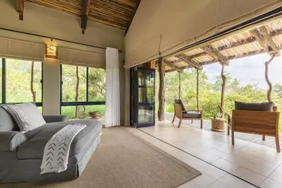 a bedroom with a bed and a couch and windows at Baobab Ridge in Klaserie Private Nature Reserve