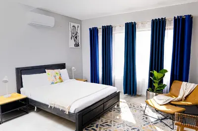 a bedroom with blue curtains and a bed and a chair at Mills Pad with 2-bedroom in Nelspruit