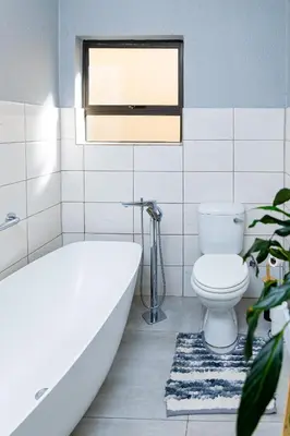 a bathroom with a tub and a toilet and a window at Mills Pad with 2-bedroom in Nelspruit