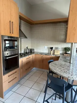 a kitchen with wooden cabinets and a table with chairs at Fish Eagle Bay 28, Warmbaths in Bela-Bela