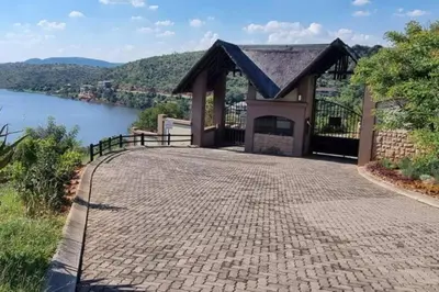 a building with a brick walkway next to a lake at Fish Eagle Bay 28, Warmbaths in Bela-Bela