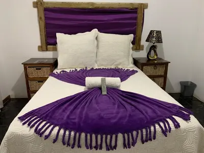 a bed with a purple and white blanket on it at Sikhula Sonke Guest House in Erasmus