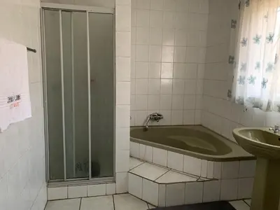 a bathroom with a shower and a tub and a sink at Sikhula Sonke Guest House in Erasmus