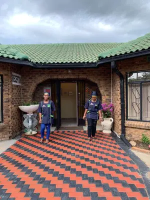 two people standing on a carpet in front of a building at Sikhula Sonke Guest House in Erasmus