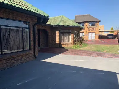 a brick house with a garage and a driveway at Sikhula Sonke Guest House in Erasmus