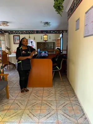 a woman standing next to a counter in a restaurant at Sikhula Sonke Guest House in Erasmus
