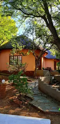 a house with a tree in front of it at Double Rondavel with Dam views in Pelindaba