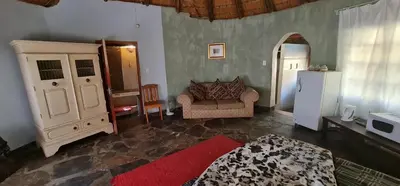 a living room with a couch and a refrigerator at Double Rondavel with Dam views in Pelindaba