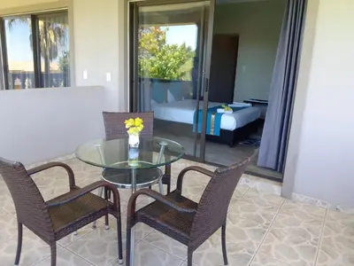 a glass table and chairs in a room with a bedroom at Palm View Midrand Guest House in Midrand