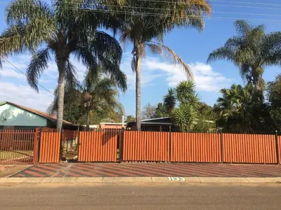 an orange fence with palm trees in front of a house at Galaxy Guest House Pretoria in Pretoria