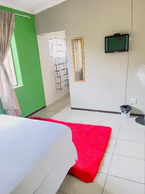 a bedroom with a red rug on the floor at Galaxy Guest House Pretoria in Pretoria