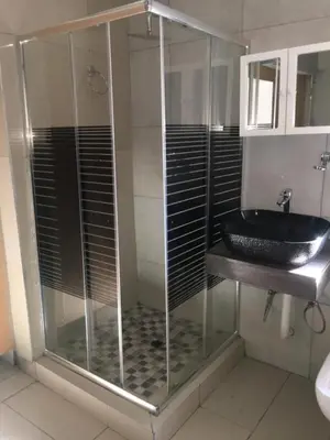 a bathroom with a glass shower with a black sink at Galaxy Guest House Pretoria in Pretoria