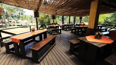 a restaurant with wooden tables and benches on a deck at Jock-Sabie Lodge in Sabie