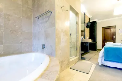 a large bathroom with a tub and a sink at OR Tambo Guest House in Kempton Park
