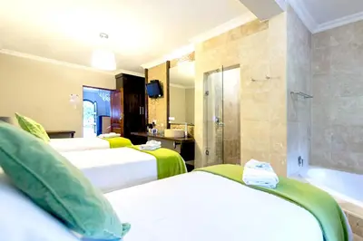 a hotel room with three beds and a bath tub at OR Tambo Guest House in Kempton Park