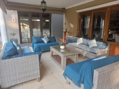 a living room with blue couches and a table at OR Tambo Guest House in Kempton Park