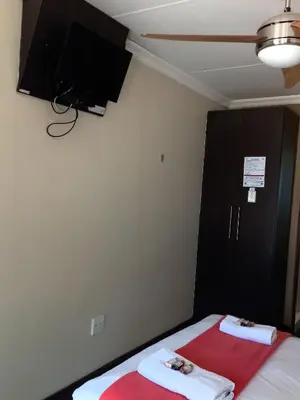 a bedroom with two beds and a tv on the wall at OR Tambo Guest House in Kempton Park