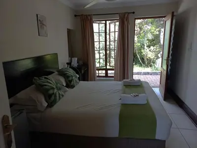 a bedroom with a large bed with a large window at OR Tambo Guest House in Kempton Park