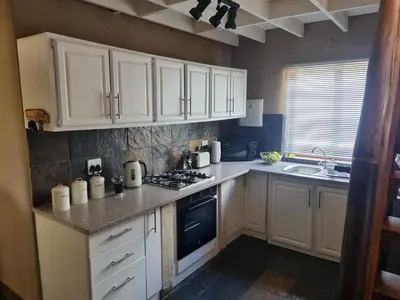 a kitchen with white cabinets and a stove top oven at Larima Bush Retreat in Hoedspruit