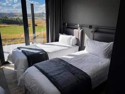 two beds in a hotel room with a large window at The Big Easy Rest at Highland Gate Golf & Trout in Dullstroom