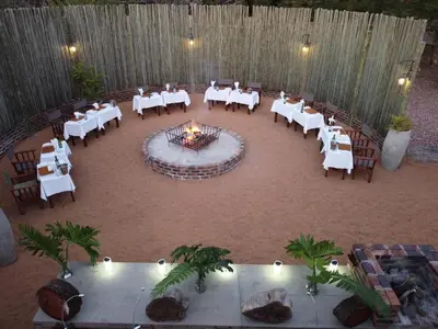 a banquet hall with white tables and chairs and a fire pit at Bushwa Private Game Lodge in Vaalwater