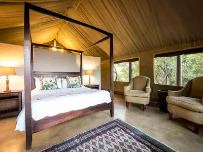 a bedroom with a canopy bed and two chairs at Bushwa Private Game Lodge in Vaalwater