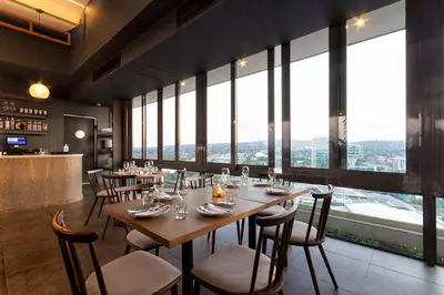 a restaurant with tables and chairs and large windows at Alimama Spaces: Koketso's Menlyn Maine in Pretoria