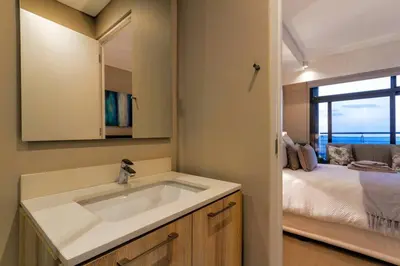 a bathroom with a sink and a bed with a window at Alimama Spaces: Koketso's Menlyn Maine in Pretoria
