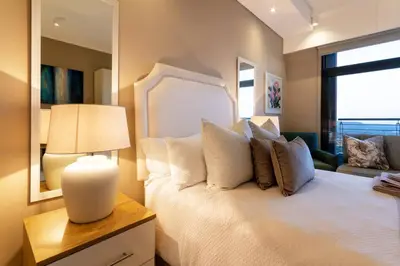 a bedroom with a white bed with a lamp and a window at Alimama Spaces: Koketso's Menlyn Maine in Pretoria