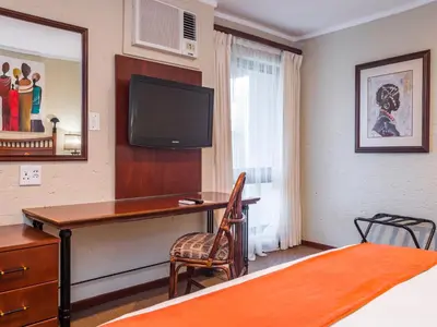 a bedroom with a desk and a tv on the wall at aha Kopanong Hotel & Conference Centre in Bredell