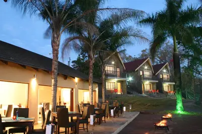 a restaurant with tables and chairs and palm trees at Destiny Lodge in White River