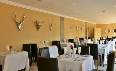 a restaurant with white tables and black chairs and antlers on the wall at Destiny Lodge in White River