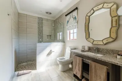 a bathroom with a toilet and a sink and a mirror at Nut Grove Boutique Hotel in White River