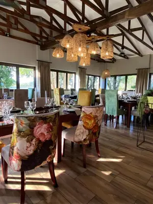 a dining room with a table and chairs and chandeliers at Nut Grove Boutique Hotel in White River