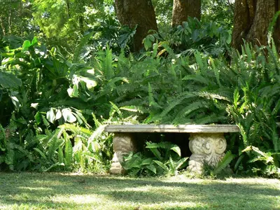 a stone bench sitting in the middle of a garden at Nut Grove Boutique Hotel in White River