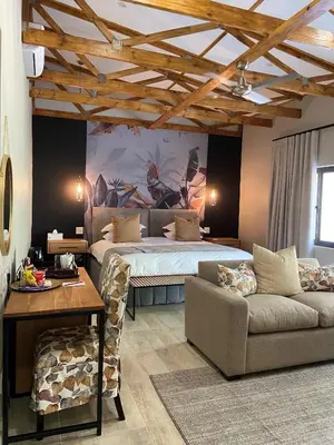 a bedroom with a bed and a couch and a table at Nut Grove Boutique Hotel in White River