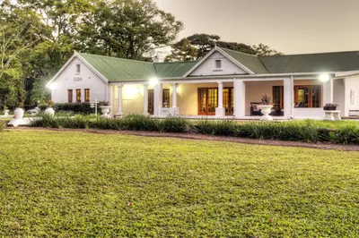 a white house with a green roof at Nut Grove Boutique Hotel in White River