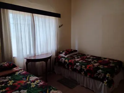 a room with two beds and a table and a window at KHAYA LANGA Guest House & Contractors Accommodation in Machadodorp