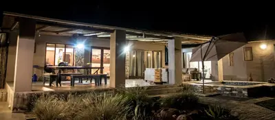 a house with a table and an umbrella at night at Buhala @ 411 in Hoedspruit