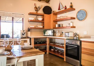 a kitchen with wooden shelves and a stove and a table at Buhala @ 411 in Hoedspruit