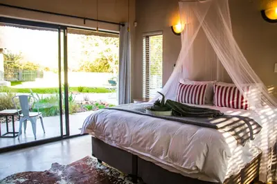a bedroom with a canopy bed and a patio at Buhala @ 411 in Hoedspruit