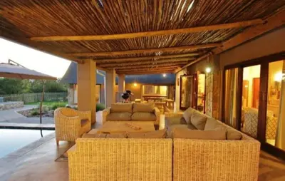 a living room with wicker furniture and a patio at Buhala @ 411 in Hoedspruit