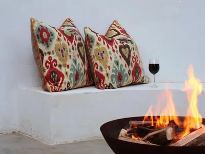 a fire pit with four pillows and a glass of wine at TWO Prefab Living - Luxury bungalows in Dullstroom