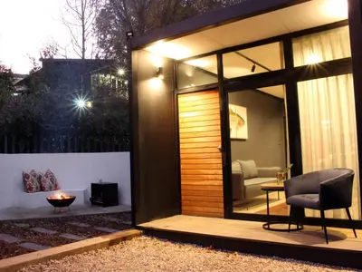 a glass extension of a house with a chair and a table at TWO Prefab Living - Luxury bungalows in Dullstroom